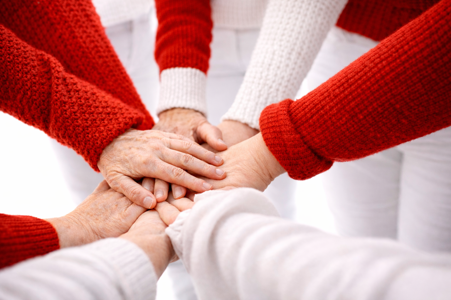 hands on top of each other in white and red sleeves